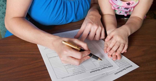 A woman filling out a child support worksheet with her daughter