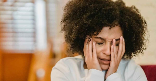 A woman with her face in her hands. She appears very frustrated