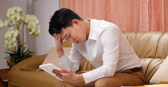 A man staring at a bill in frustration