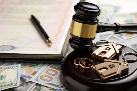 a gavel, house keychains, wedding rings, money, and divorce papers
