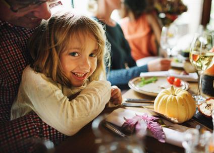child sitting on parent's lap at the Thanksgiving table